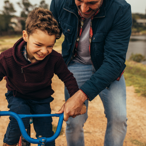 father helping son ride bike father helping son ride bike